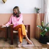 a serious beautiful businesswoman in pink shirt and orange trousers taking notes while relaxing at home - home decoration stockfoto's en -beelden