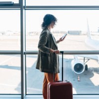 a side view of an unrecognizable busy elegant businesswoman using her mobile phone to talk to her business partners while waiting for her flight - travel stock pictures, royalty-free photos & images