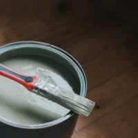 a small paintbrush sits on top of a large tin of light green / grey paint - home decoration stock pictures, royalty-free photos & images