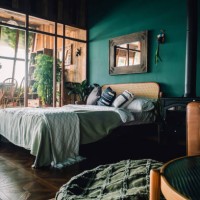 a stylish loft bedroom interior with brown coloured rattan furniture and wooden elements with dark green coloured wall. decorated with plants - home decoration stockfoto's en -beelden