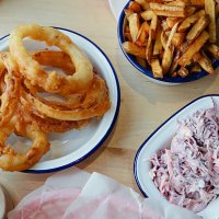a table full of junk food, burgers, onion rings - junk food fotografías e imágenes de stock