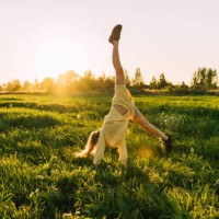 a teenage girl with curly hair dance in a field at sunset. - fashion stock pictures, royalty-free photos & images