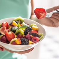 a woman breakfasts a fruit salad high in vitamins and fiber. - food stock pictures, royalty-free photos & images