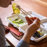 a woman eating a take-out lunch box at her table at home. - junk food stock pictures, royalty-free photos & images