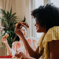 a woman enjoys a slice of pizza with a friend - junk food stock pictures, royalty-free photos & images