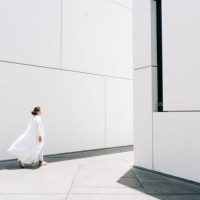 a woman in a white dress walks near a white minimalist building. - fashion stock pictures, royalty-free photos & images