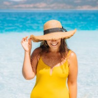 a woman in a yellow swimsuit and straw hat emerges from the sea with clear turquoise water on a summer sunny day. - fashion stock pictures, royalty-free photos & images