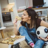 a woman watches football and cheers for her team - junk food stock pictures, royalty-free photos & images