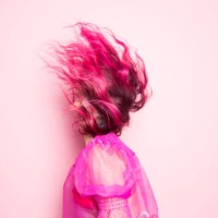 a woman with pink hair throws her head back so that her hair covers her face in front of a pink background - fashion stock pictures, royalty-free photos & images