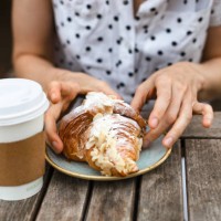a woman with polka dot shirt, eating a croissant - junk food stock pictures, royalty-free photos & images