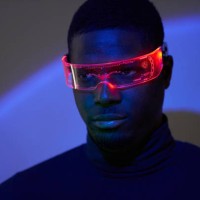 a young african-american man in futuristic fashion glasses with neon light looks away. the concept of the future, computer games, augmented reality, virtual reality, modern technologies, technological progress. - fashion stoc