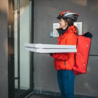 a young caucasian female delivery girl carries pizza boxes - junk food stock pictures, royalty-free photos & images