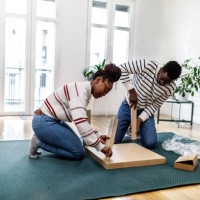 a young couple of afro-americans is assembling new furniture in their house. - home decoration stock pictures, royalty-free photos & images