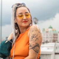 a young happy independent woman with long colored dreadlocks and a tattoo on her shoulder poses on a city street. - fashion stock pictures, royalty-free photos & images