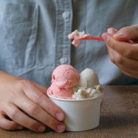 a young man, a guy eats ice cream in a cafe, cafeteria, in a chain of fast food restaurants. vegan ice cream in the hands of a high school student. vanilla and berry sherbet, dessert. the concept of rest and relaxation, vacat
