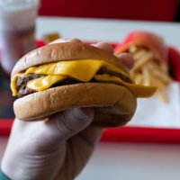 a young man is holding a piece of hamburger in his hands. a guy or a man eats fast food. a hungry skinny guy is eating an appetizing burger. the concept of unhealthy food, diet, overeating, gluttony, dependence on food. fast 