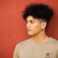 a young man leans against a wall and looks to his right side - hairstyle stock pictures, royalty-free photos & images