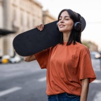 a young spanish woman with a skateboard walks down the street - fashion stock pictures, royalty-free photos & images