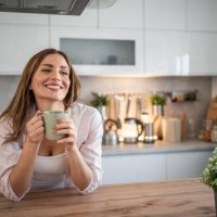 a young woman enjoys her kitchen, dressed in pajamas, drinking her morning coffee - coffee stockfoto's en -beelden