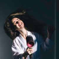a young woman in white bathrobe blow-dries her hair at home. - hairstyle stockfoto's en -beelden