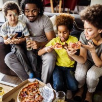 above view of happy black family eating pizza at home. - junk food stock pictures, royalty-free photos & images