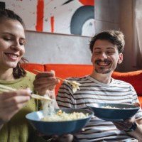 adorable young caucasian couple sharing their chinese take out food - junk food stock pictures, royalty-free photos & images
