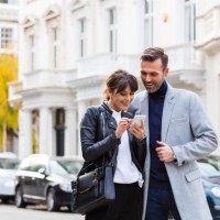 adult couple using smart phone together in the city street - fashion stock pictures, royalty-free photos & images