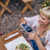 adult hipster female sitting outside in the restaurant, using a phone to take a picture of her caesar salad. - food stock pictures, royalty-free photos & images