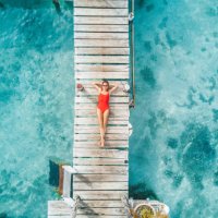 aerial shot of womann relaxing in a water bungalow - travel stock pictures, royalty-free photos & images