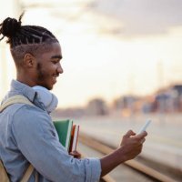 african american male student waiting for a train and checking smart phone - hairstyle stock pictures, royalty-free photos & images