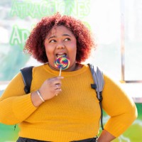 african american woman enjoying licking a rainbow candy lollipop - junk food stock pictures, royalty-free photos & images