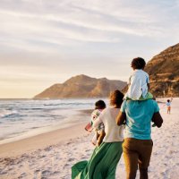 african parents with little kids bonding and strolling by ocean. little children enjoying the outdoors during their summer holidays or vacation. rear of a family walking on the beach with copy space - travel stock pictures, r