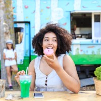 african woman eating donut and drinking coctail in nature - junk food stock pictures, royalty-free photos & images