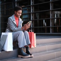 african woman using the mobile sitting with shopping bags - fashion stock pictures, royalty-free photos & images
