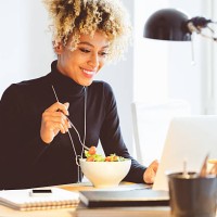 afro american young woman eating lunch at the desk - food stockfoto's en -beelden