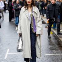 Alexa Chung wears trench coat, silver sequined bag, blue striped pants outside JW Anderson during London Fashion Week February 2024 on February 18,...