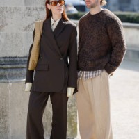 Alice Barbier wears brown suit, beige shirt and tie, beige Bottega Veneta bag, snake skin print heels, and js Roques wears brown sweater, beige...
