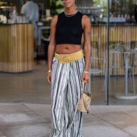 Amaka Hamelijnck wears black cropped top, striped pants, belt, beige bag outside Marimekko during day four of the Copenhagen Fashion Week SS25 on...