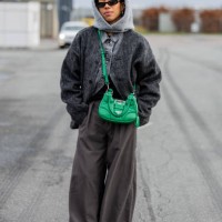 Amaka Hamelijnck wears grey balaclava, green bag, denim jeans jacket, grey wide leg pants outside Marimekko during the Copenhagen Fashion Week...