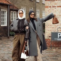 Amaka Hamelijnck wears wide brown pants, dark brown leather jacket, white hat and cow print bag and Benthe Liem wears beige pants, black turtle neck,...