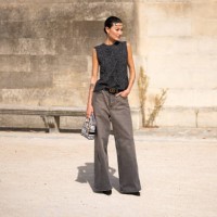 Amalie Gassmann wears a grey knitted vest, grey jeans, Dior belt, black heels and Dior printed bag, outside Dior, during the Womenswear Spring/Summer...