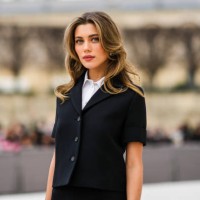 Amelie Zilber wears a white short sleeves shirt from Dior, a black short sleeves buttoned jacket from from Dior, a black short skirt from from Dior,...