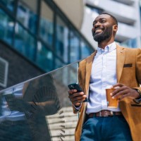 an adult handsome black businessman outside of corporation, using phone - fashion fotografías e imágenes de stock