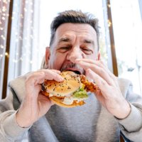an adult man eating a burger in a cafe. - junk food stock pictures, royalty-free photos & images