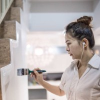an asia chinese women listening music and painting walls using paint brush in her new house. home makeover and renovation concept. - home decoration stock pictures, royalty-free photos & images