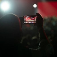 An attendee takes a photo with their smartphone as the musicians of Rockin'1000 perform live on September 30, 2021 in Milan, Italy. A free...