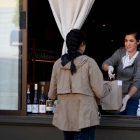 An employee for Atelier Crenn restaurant hands a takeout order to a customer through a window in San Francisco, California on April 2020, during the...