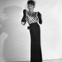 An eye-catching bodice of black and pink striped satin, embroidered with jet, tops the slim black crepe skirt of this Hattie Carnegie model. The...