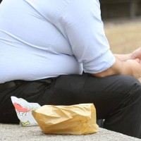 An overweight man eats fast food. GPs and other health professionals should tell people they are fat rather than obese, a health minister said today.