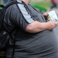 An overweight man with an obscured face eats crisps on March 29, 2009 in Cardiff, United Kingdom.